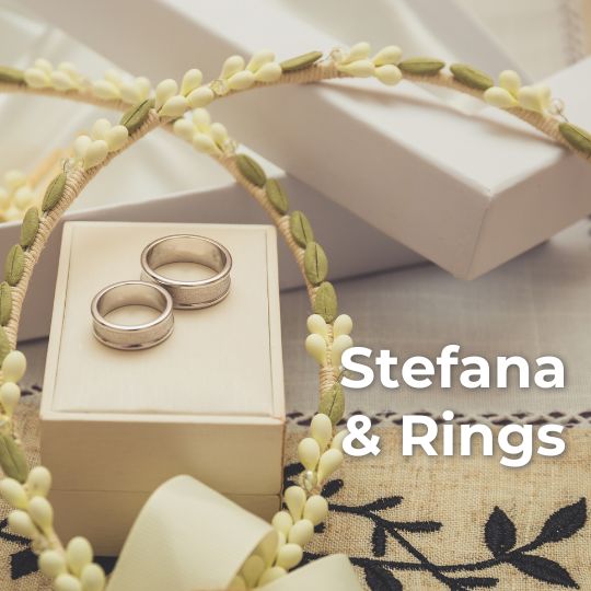 Two
                      wax orange blossom stefana (Greek wedding Crowns)
                      with a pair of silver wedding rings on a white
                      ring box