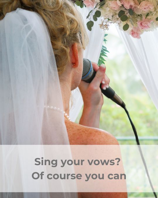 Blonde bride, wearing a veil attached to the
                      back of her head and a string of pearls, singing
                      into a corded microphone.