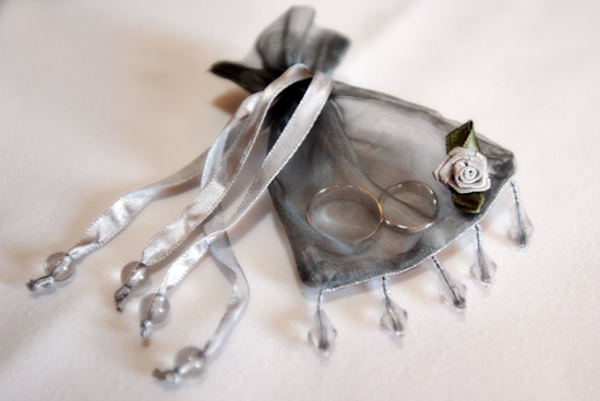 Wedding rings in a silver organza ring
                        bag trimmed with beads and silk roses